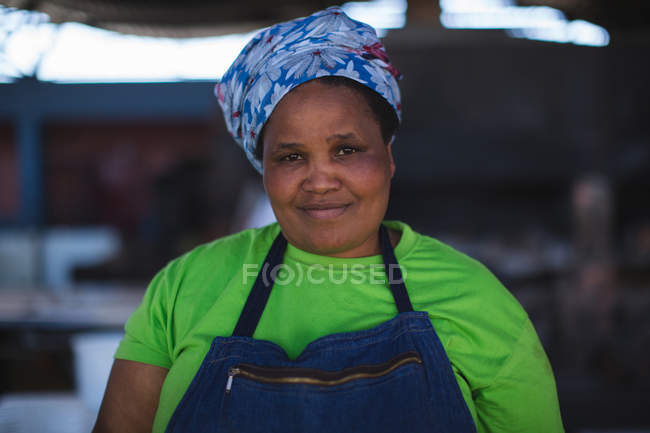Boucher féminin souriant debout à la boucherie — Photo de stock