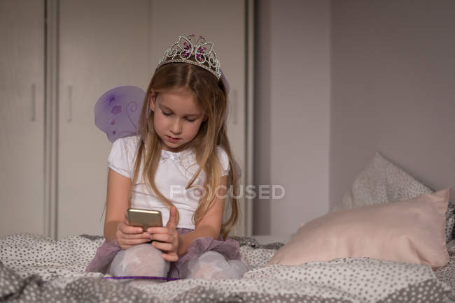 Fille en utilisant téléphone portable dans la chambre à coucher à la maison — Photo de stock