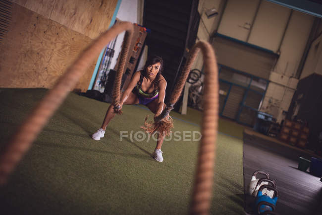 Fit mulher fazendo exercício de corda de batalha no ginásio — Fotografia de Stock