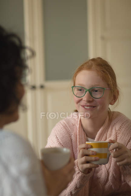 Madre e hija tomando café en la sala de estar en casa - foto de stock