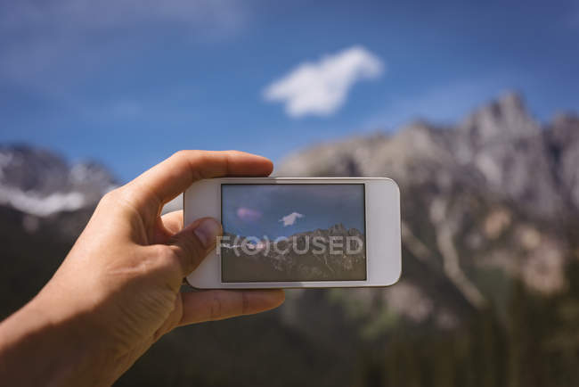 Крупним планом чоловік фотографує гори з мобільним телефоном — стокове фото