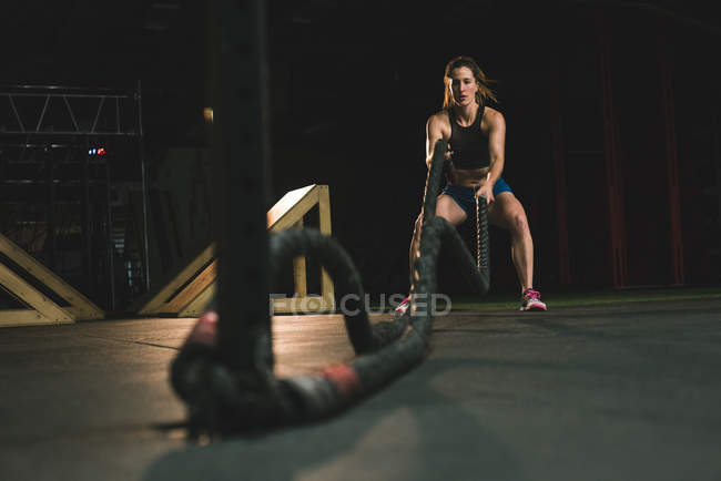 Muscular woman exercising with battle rope at gym — Stock Photo