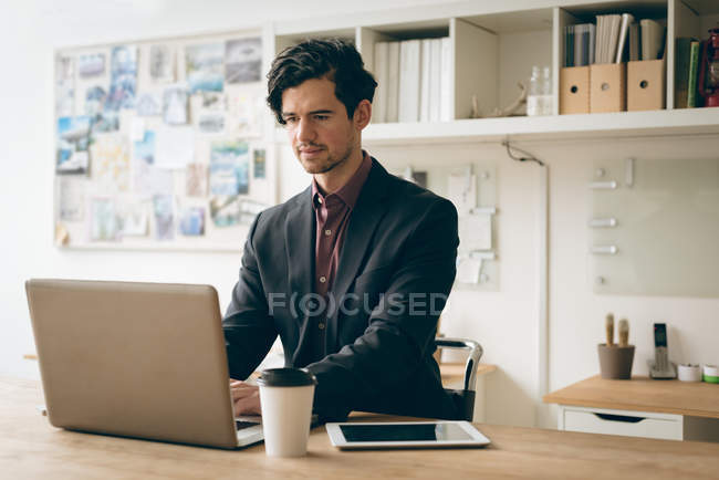 Male executive working on laptop in office — Stock Photo