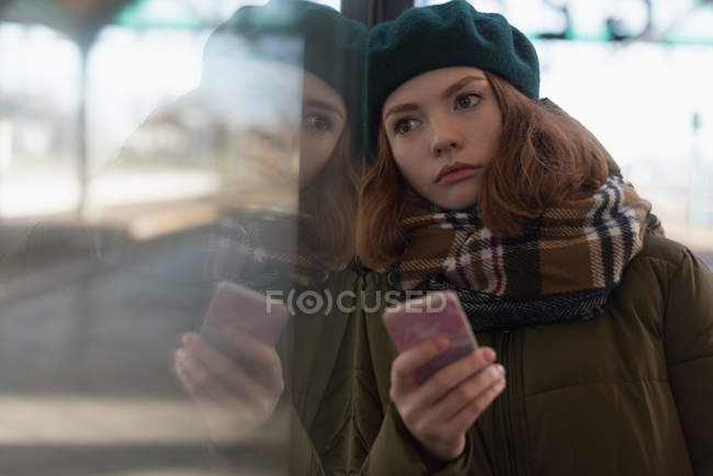 Mulher pensativa em roupas de inverno apoiando-se na parede de vidro na estação ferroviária — Fotografia de Stock