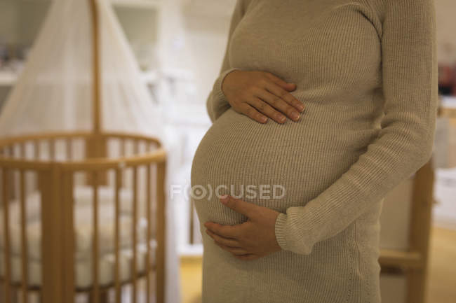 Partie médiane de la femme enceinte touchant son ventre en magasin — Photo de stock