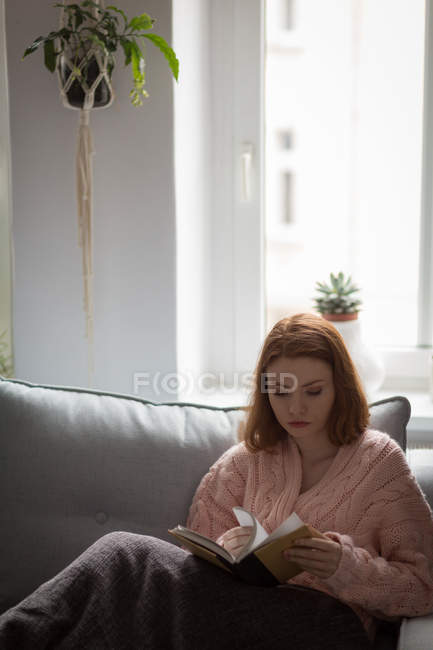 Молода жінка перевертає сторінки книги вдома — стокове фото