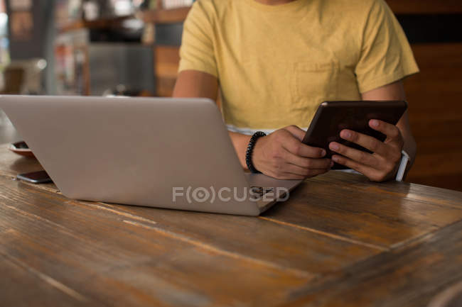 Mid section of man using digital tablet in cafeteria — Stock Photo