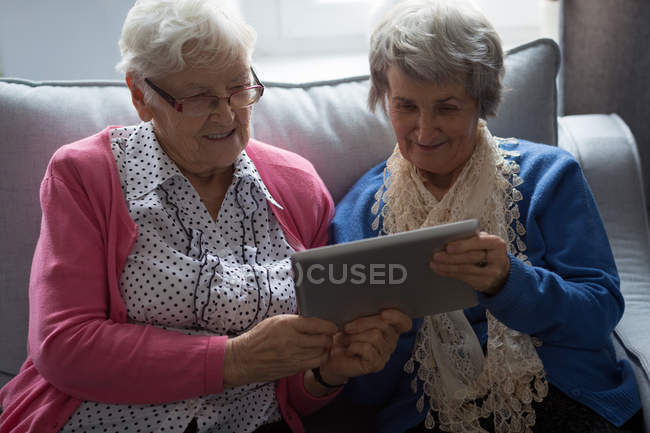 Amis seniors utilisant une tablette numérique à la maison — Photo de stock