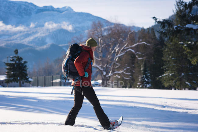 Donna che cammina su un paesaggio innevato in una giornata di sole — Foto stock