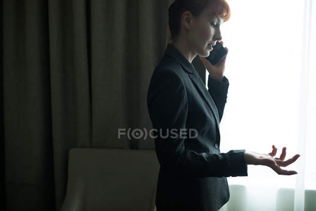 Donna d'affari che parla al cellulare in camera d'albergo — Foto stock