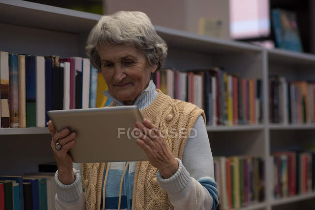 Mulher idosa ativa usando tablet digital na biblioteca — Fotografia de Stock