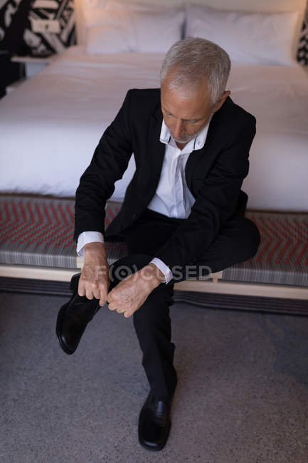 Бизнесмен завязывает шнурки в номере отеля — стоковое фото