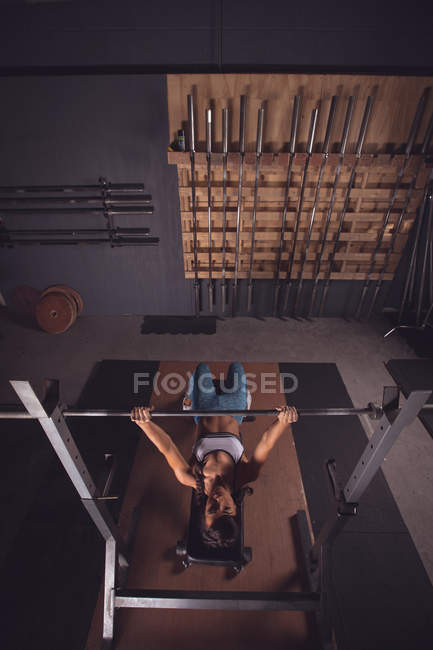 Fit femme soulevant la tige d'haltère dans la salle de gym — Photo de stock