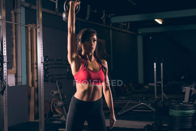 Mujer en forma haciendo ejercicio con kettlebell en el gimnasio - foto de stock