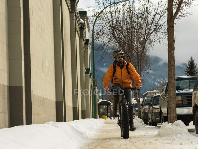 Man riding his bicycle on sidewalk during winter — Stock Photo