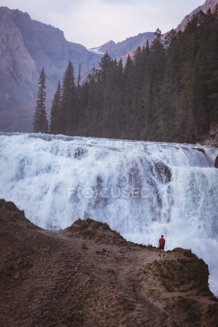 Uomo con zaino guardando cascata — Foto stock