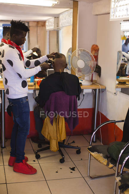 Barber trimming customer hair in barber shop — Stock Photo
