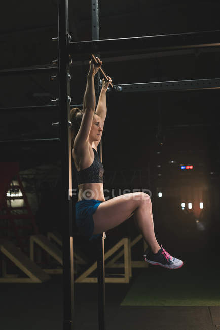М'язиста жінка тренується тягнути вгору на барі в спортзалі — стокове фото