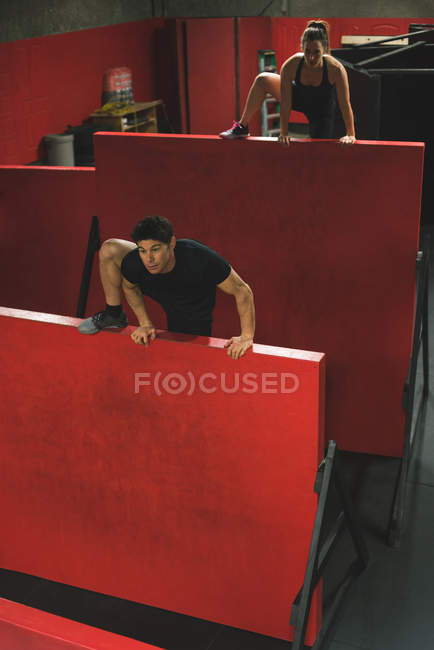 Casal muscular escalando uma parede de escalada no ginásio — Fotografia de Stock