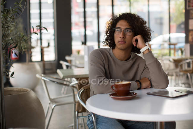 Вдумчивый молодой человек отдыхает в кафетерии — стоковое фото