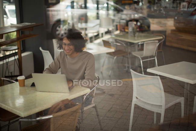 Homme heureux utilisant un ordinateur portable à la cafétéria — Photo de stock