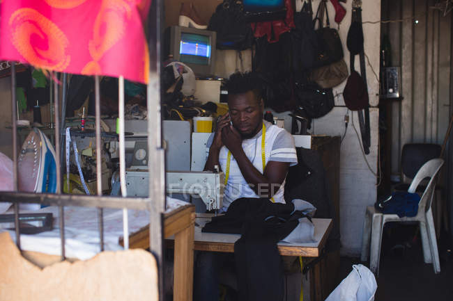 Tailor hablando por teléfono móvil en la tienda - foto de stock