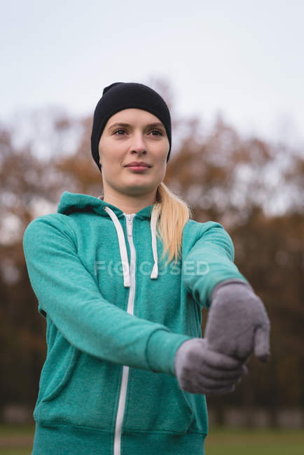 Jeune femme effectuant des exercices d'étirement dans le parc — Photo de stock