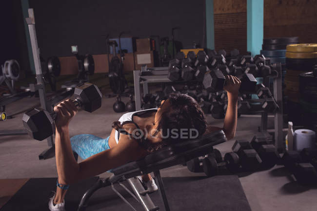 Підійде жінка, займається з гантелями в спортзалі — стокове фото