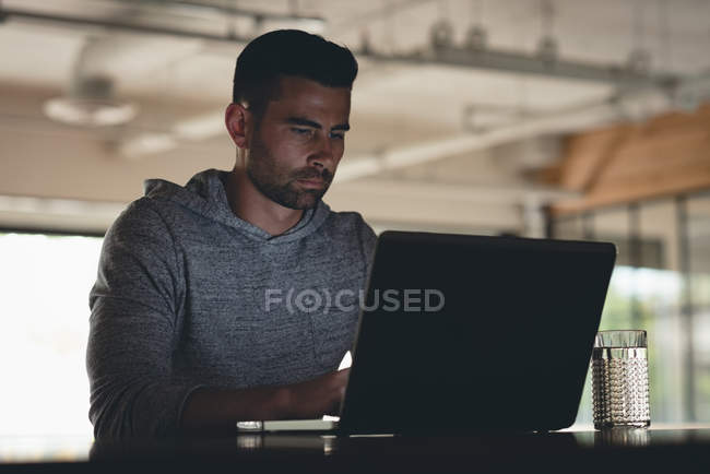 Homme d'affaires utilisant un ordinateur portable à la cafétéria au bureau — Photo de stock