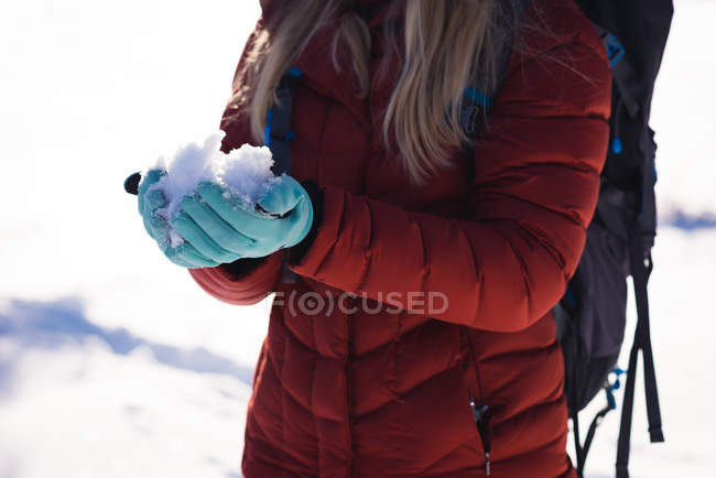 Metà sezione di donna che tiene una mano piena di neve — Foto stock
