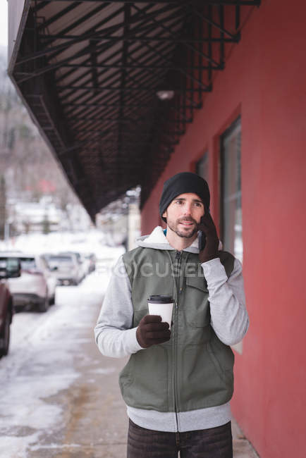Молодой человек разговаривает по мобильному телефону возле магазина — стоковое фото