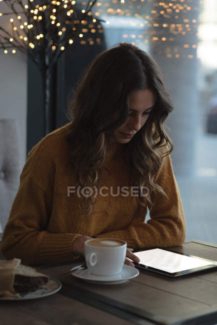 Young woman using digital tablet in restaurant — Stock Photo