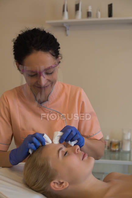 Beautician giving beauty treatment to female customer with a machine in parlour — Stock Photo