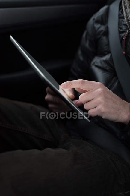 Средняя часть человека с помощью цифрового планшета в автомобиле — стоковое фото