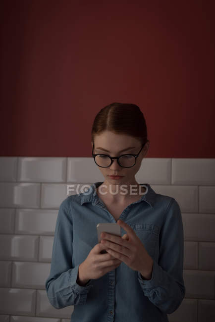 Женщина с помощью мобильного телефона на кухне дома — стоковое фото