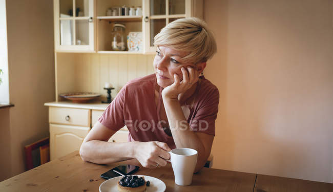 Mulher atenciosa tomando café da manhã em casa — Fotografia de Stock