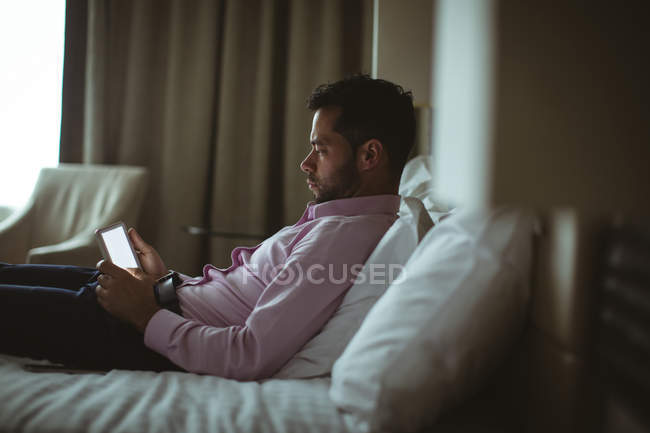 Homme d'affaires utilisant une tablette numérique dans la chambre d'hôtel — Photo de stock