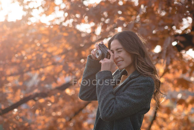 Молода жінка фотографується з камерою в парку — стокове фото