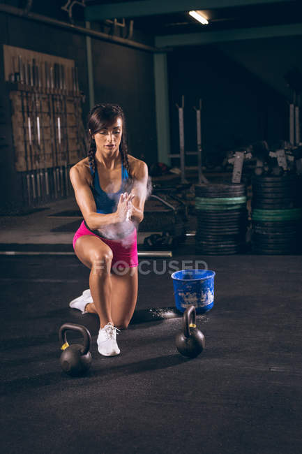 Mujer en forma que limpia sus manos con polvo de tiza en el gimnasio - foto de stock