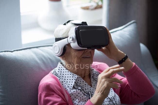 Старшая женщина использует гарнитуру виртуальной реальности дома — стоковое фото