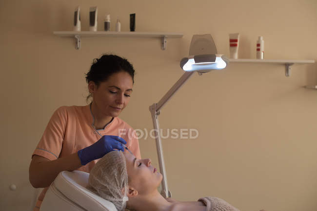 Косметолог дає догляд за красою для жінок-клієнтів у вітальні — стокове фото