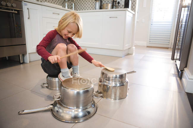 Menino brincando com utensílios na cozinha em casa — Fotografia de Stock