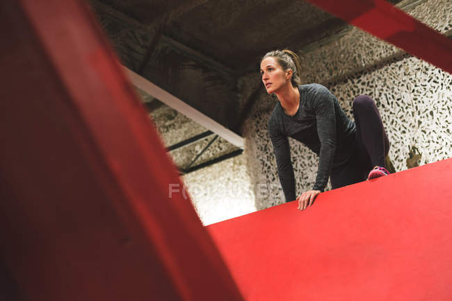 Muscular woman climbing a wall in the gym — Stock Photo
