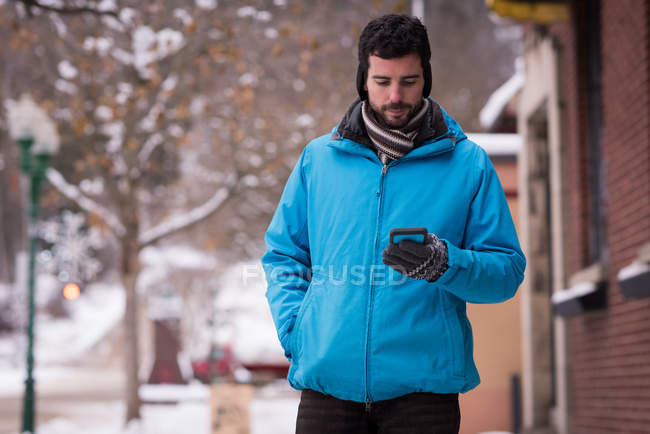 Homem usando telefone celular na cidade durante o inverno — Fotografia de Stock