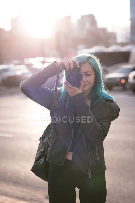 Mujer elegante fotografiando con cámara en la calle de la ciudad - foto de stock