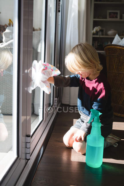 Boy cleaning window with rag cloth at home — Stock Photo