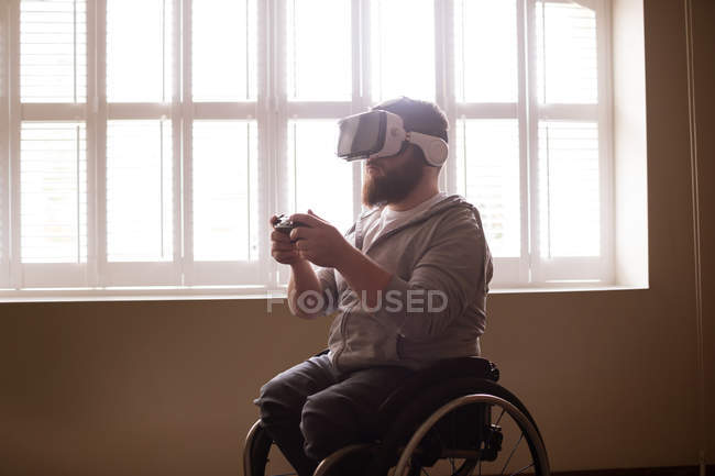 Homem com deficiência usando fone de ouvido de realidade virtual em casa — Fotografia de Stock