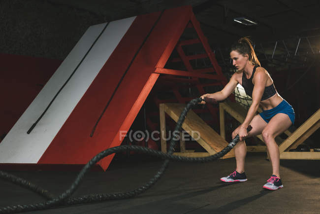 Donna muscolosa che si allena con la corda da battaglia in palestra — Foto stock