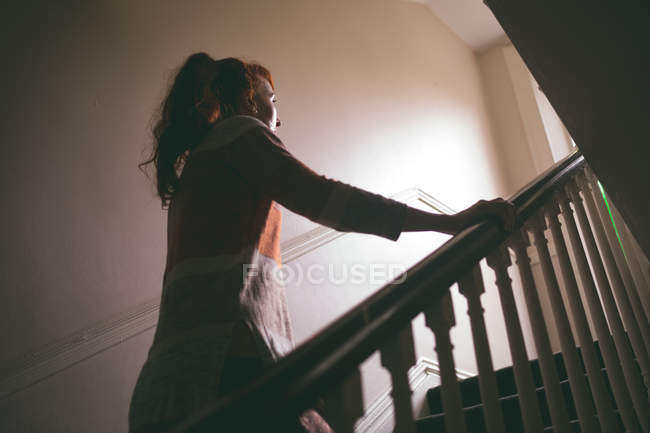 Beautiful woman walking upstairs at home — Stock Photo