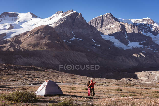 Пара стоящих рядом с палаткой в солнечный день — стоковое фото